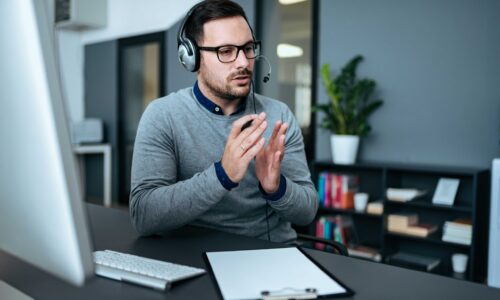 Young handsome male customer support phone operator with headset working in his office.